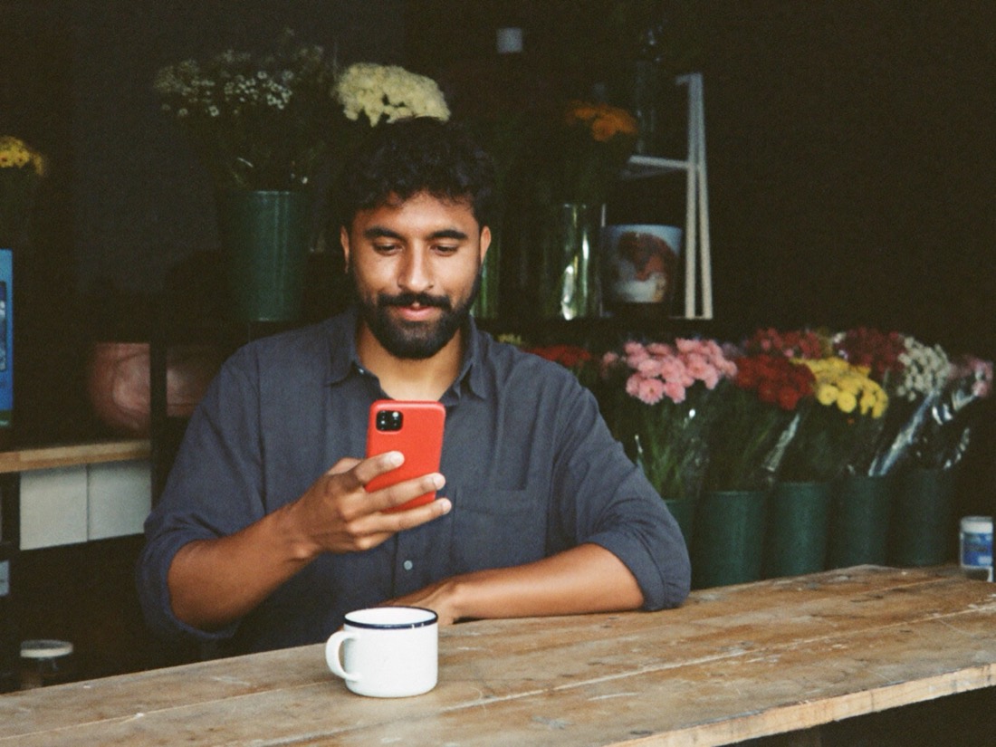 Flower shop owner calmly reading his phone after closing